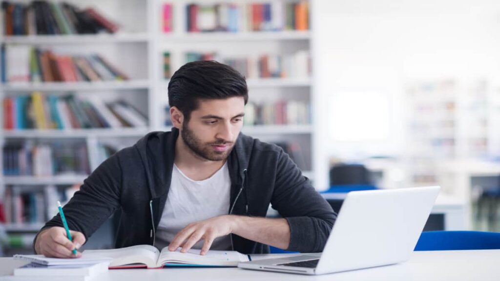 Man studying with a book and a laptop